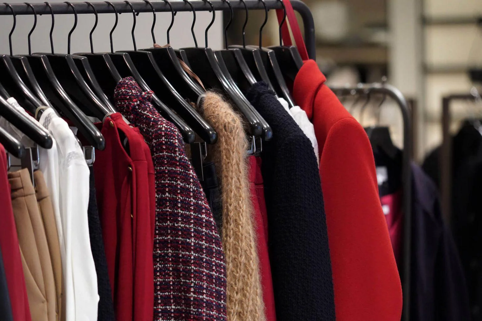 Vêtements alignés sur des cintres sur un portant à vêtement noir.