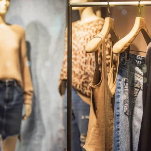 Quelques vêtements alignés sur des cintres sur un portant à vêtement et 2 tenus complètes sur des mannequins.